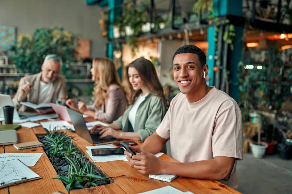 Pessoas criativas multirraciais em um escritório moderno. Grupo de jovens empresários e chefe sênior trabalhando juntos com laptop, tablet, smartphone, notebook e gráficos. Equipe de sucesso em coworking