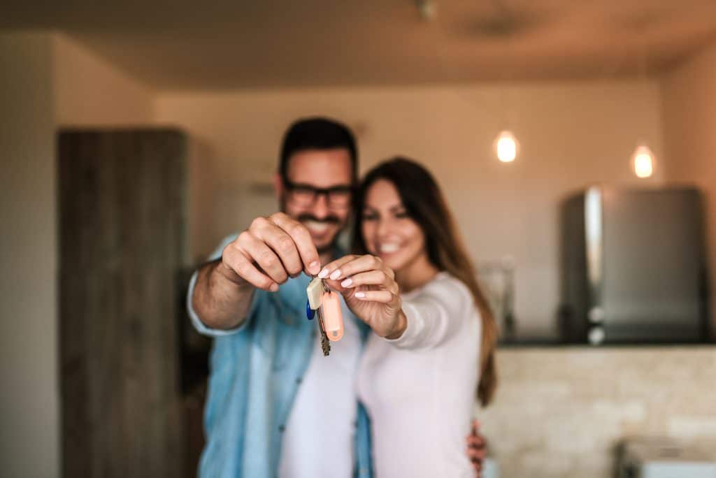 Imagem de um casal segurando um par de chaves, dando a entender que acabaram de comprar um imóvel